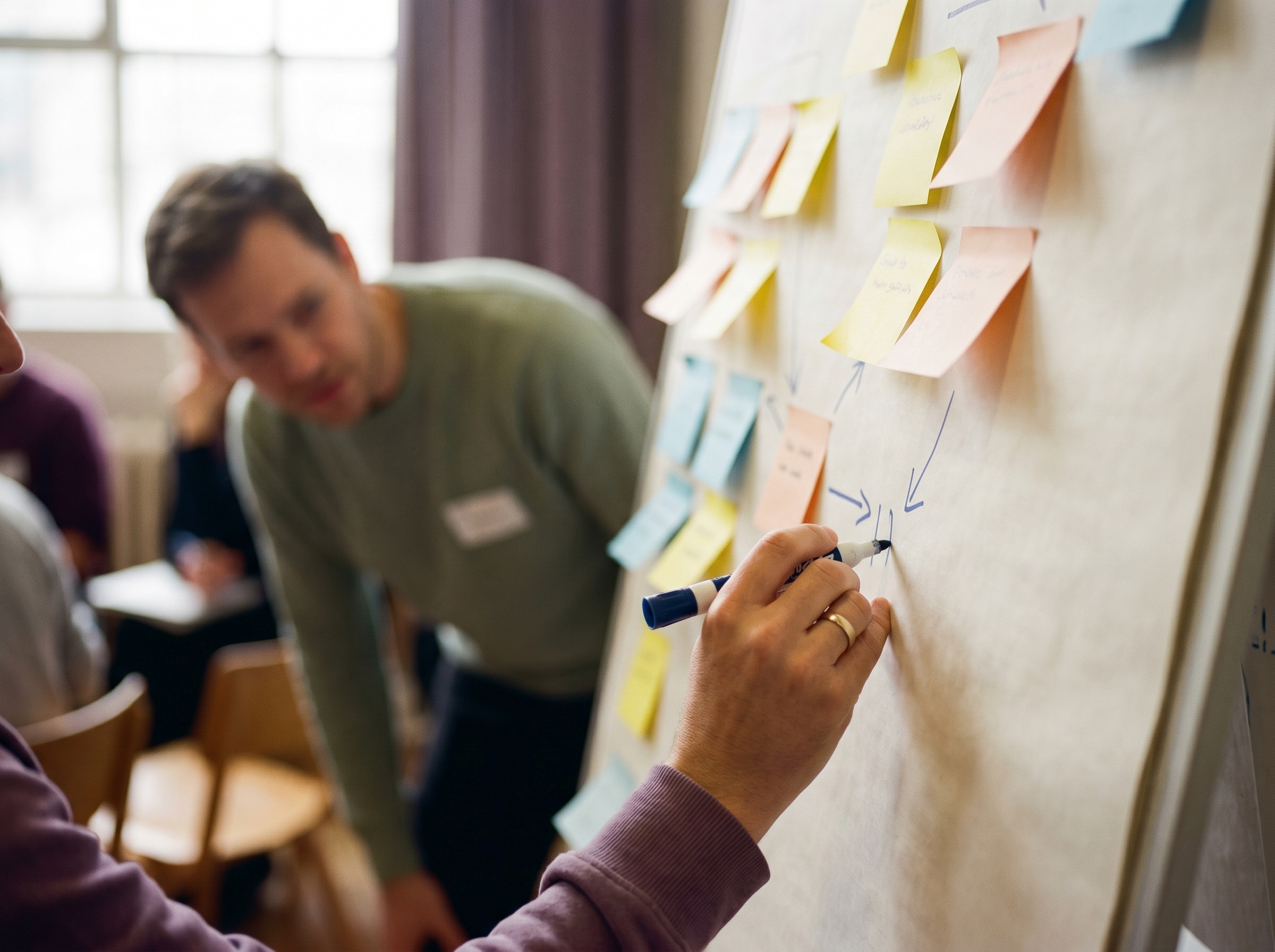 Iemand schrijft aantekeningen op een whiteboard met post-its